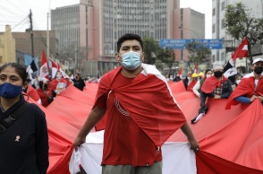 Διαδηλωτής στο Περού με κόκκινη μπλούζα και μάσκα προστασίας