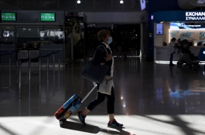 Γυναίκα με βαλίτσα φορά τη μάσκα κατά την παραμονή τους στους χώρους του αεροδρομίου