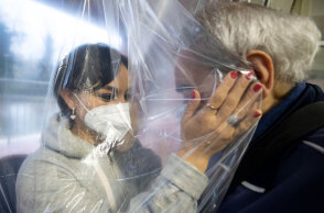 Γυναίκα με μάσκα στην Ιταλία αγκαλιάζει ηλικιωμένο σε γηροκομείο, έχοντας ανάμεσά τους μια ειδική πλαστική κουρτίνα