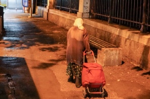 Ηλικιωμένη σέρνει το καρότσι της σε δρόμο 