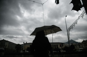 Κακοκαιρία: Γυναίκα κρατά ομπρέλα για να προστατευτεί από την καταιγίδα