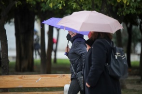 Γυναίκες περπατούν στο κέντρο της Αθήνας κρατώντας ομπρέλες