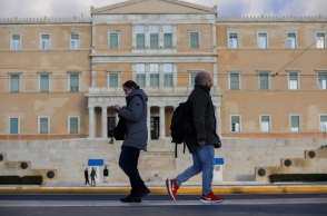 Άνδρας και Γυναίκα περπατούν στο κέντρο της Αθήνας με φόντο τη Βουλή των Ελλήνων