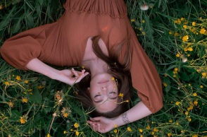 Ένα κορίτσι ξαπλώνει στο γρασίδι και ποζάρει. 