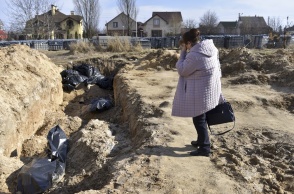 Γυναίκα στέκεται συγκλονισμένη πάνω από ομαδικό τάφο στην Μπούκα της Ουκρανίας
