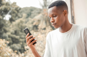 Μια φωτογραία ενός άνδρα να κρατάει ένα κινητό τηλέφωνο.