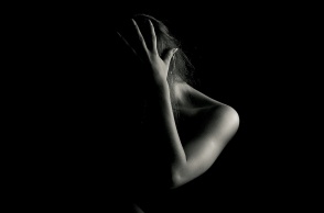 Γυναίκα φωτογραφίζεται με το χέρι στο πρόσωπο σε σκοτάδι - Φαίνεται ο ώμος και το χέρι της