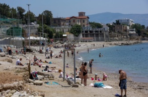 Λουόμενοι σε παραλία απολαμβάνουν την ηλιοθεραπεία τους - Ζέστη στην Αττική τον Μάιο του 2022
