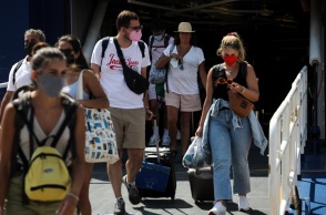 Επιβάτες αποβιβάζονται από πλοίο φορώντας μάσκες