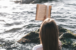 Κοπέλα που διαβάζει βιβλίο στη θάλασσα