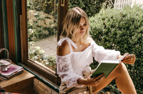 Μια κοπέλα κάθεται στο παράθυρο και διαβάζει ένα βιβλίο