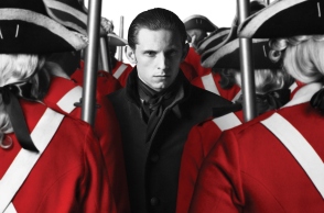 Άντρας με μαύρα ρούχα ανάμεσα σε στρατιώτες με κόκκινη στολή