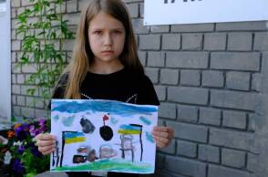 Ένα κορίτσι από την Ουκρανία κρατάει μια ζωγραφιά για τον πόλεμο της Ρωσίας στη χώρα της