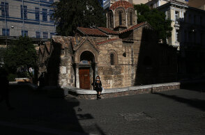 Σκληρό lockdown στην Αττική για τον κορωνοϊό έως τις 28 Φεβρουαρίου 2021 - Κοπέλα με μάσκα κάθεται στο πεζούλι μπροστά από την Καπνικαρέα, την ιστορική εκκλησία στην Ερμού