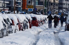 Κακοκαιρία «Ελπίδα»: Πολίτες περπατούν πάνω στη Μεσογείων λόγω του χιονιού που βρίσκεται στα πεζοδρόμια