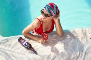 Γυναίκα σε πισίνα κρατάει ποτήρι με Spritz Veneziano και δίπλα είναι το μπουκάλι Select Aperitivo