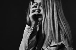 Ασπρόμαυρη φωτογραφία κοπέλας που κρύβει το πρόσωπό της με το χέρι της