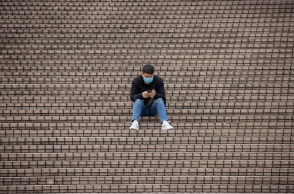 Πολίτης με μάσκα προστασίας από τον κορωνοϊό κάθεται σε σκαλιά