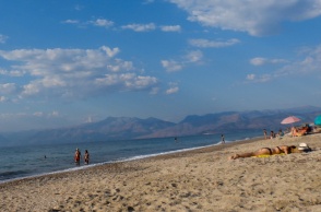 Λουόμενοι απολαμβάνουν τον ήλιο σε παραλία - Λίγα σύννεφα στον ουρανό