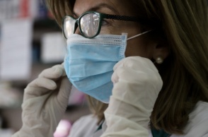 Γυναίκα με μάσκα και γάντια για την προστασία της από τη γρίπη