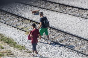 Μετανάστες περπατούν δίπλα στις γραμμές τρένου