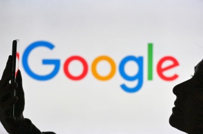 Άτομο κρατά ένα κινητό μπροστά από το λογότυπο της Google