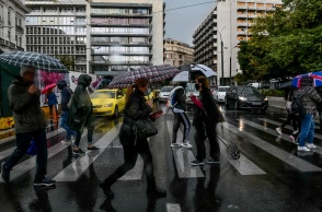 Πολίτες με ομπρέλα προστατεύονται από τη βροχή ενώ περπατούν σε δρόμο του κέντρου της Αθήνας