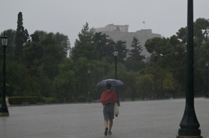 Άτομο σε δρόμο της Αθήνας κρατά ομπρέλα για να προστατευτεί από ισχυρή καταιγίδα