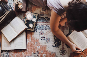 Άντρας ξαπλωμένος μπρούμυτα στο πάτωμα διαβάζει βιβλίο