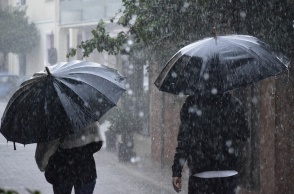 Πολίτες προστατεύονται με ομπρέλα από την ισχυρή βροχόπτωση