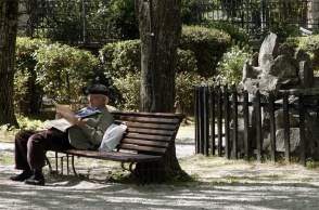 Συνταξιούχος διαβάζει την εφημερίδα του καθισμένος σε παγκάκι