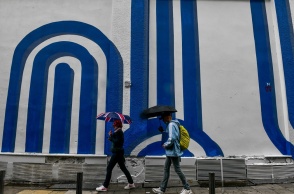 Πολίτες με ομπρέλα προστατεύονται από τη βροχόπτωση σε δρόμο της Αθήνας