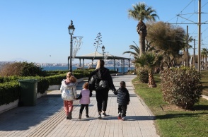 Μητέρα με τα τρία της παιδιά απολαμβάνουν τον καλό καιρό και τον ήλιο περπατώντας δίπλα στη θάλασσα