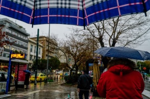 Πολίτες με ομπρέλα προστατεύονται από τη βροχή στο κέντρο της Αθήνας