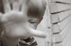 Παιδί προτάσσει το χέρι του και σφίγγει τα μάτια του υπό την απειλή φόβου