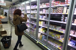 Γυναίκα μπροστά από ψυγείο σούπερ μάρκετ με γαλακτοκωμικά προϊόντα