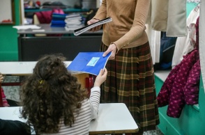 Μαθήτρια παίρνει το τετράδιο της από τη δασκάλα της σε αίθουσα δημοτικού σχολείου