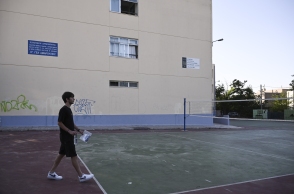 Μαθητής σε προαύλιο σχολείου με κάποια έγγραφα ανά χείρας