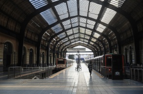 Συρμοί του ηλεκτρικού στον σταθμό του Πειραιά και μία γυναίκα που περπατά στην αποβάθρα