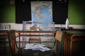 Κάλπη στερεωμένη σε δύο καρέκλες μπροστά από τον χάρτη της Ελλάδας