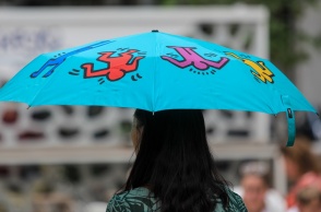 Γυναίκα με μπλε ομπρέλα προστατεύεται από τη βροχή