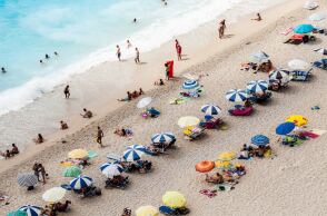 Λουόμενοι απολαμβάνουν τον ήλιο, το κολύμπι και τα παιχνίδια σε παραλία της Λευκάδας - Στημένες ομπρέλες και απλωμένες πετσέτες στην αμμουδιά