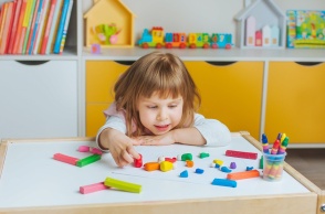Παιδί παίζει με πλαστελίνες σε τραπεζάκι παιδικού σταθμού