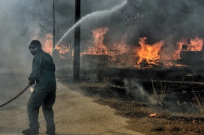 Άνδρας με μάνικα επιχειρεί για την κατάσβεση φωτιάς στο Λουτράκι