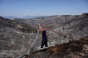 Πυροσβέστης επιχειρεί με μάνικα σε σημείο όπου η φωτιά σβήνει 
