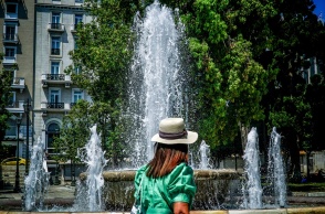 Γυναίκα με καπέλο μπροστά από το σιντριβάνι στην πλατεία Συντάγματος