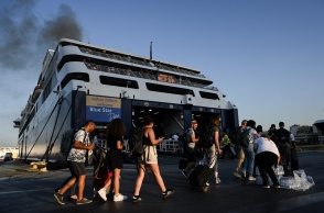 Πολίτες με βαλίτσες ετοιμάζονται για την επιβίβασή του σε πλοίο στο λιμάνι του Πειραιά