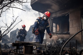 Πυροσβέστες περπατούν δίπλα σε καμένα σπίτια