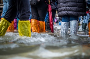 Πολίτες με προστατευτικά αδιάβροχα στα πόδια σε πλημμυρισμένο δρόμο