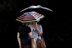 Γυναίκες κρατούν ομπρέλα για να προστατευτούν από τη βροχή και μιλάνε